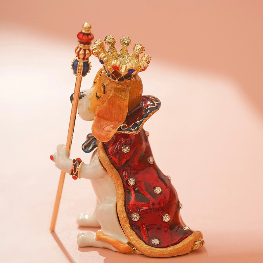 Decorative figurine of a dog dressed as a king with a crown and scepter on a pink background