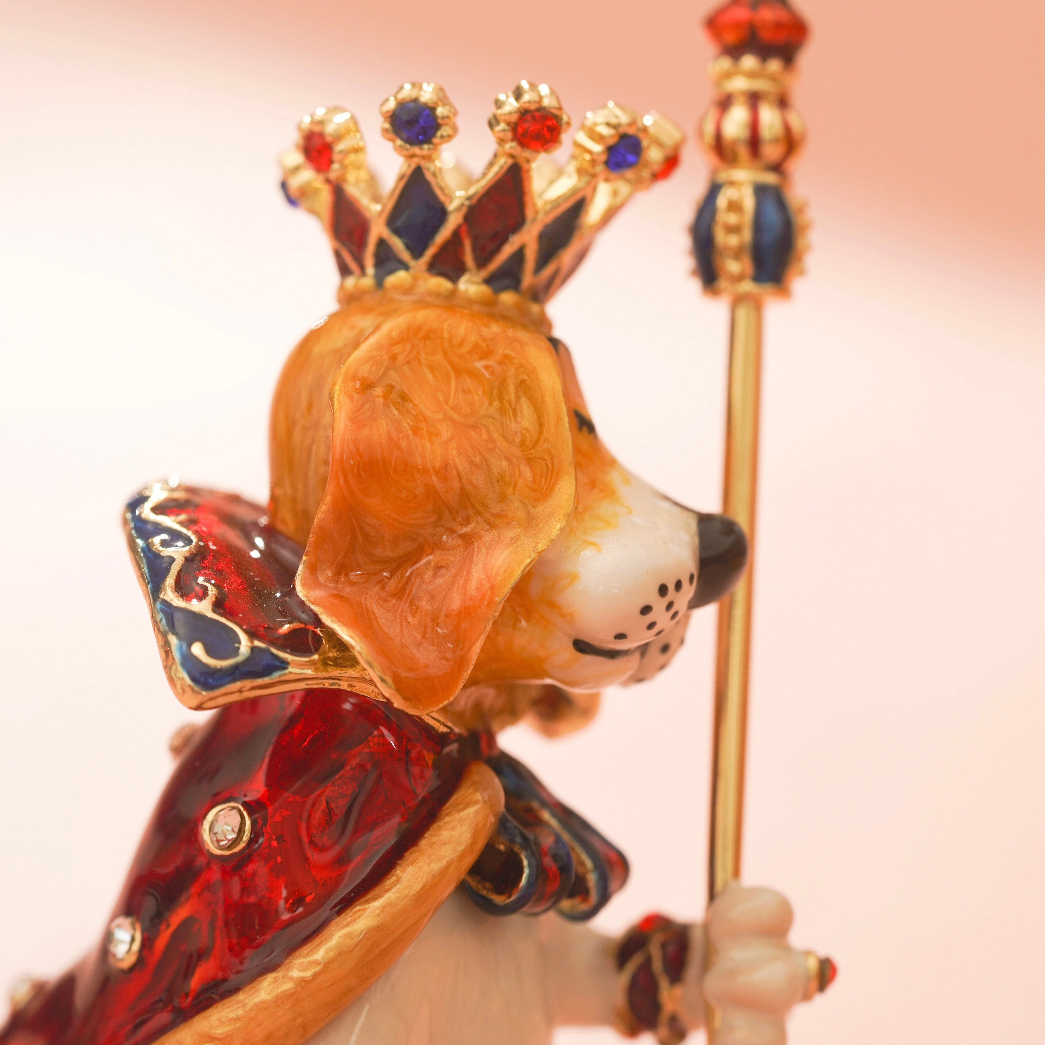 Decorative figurine of a dog wearing a crown and holding a scepter on a light pink background