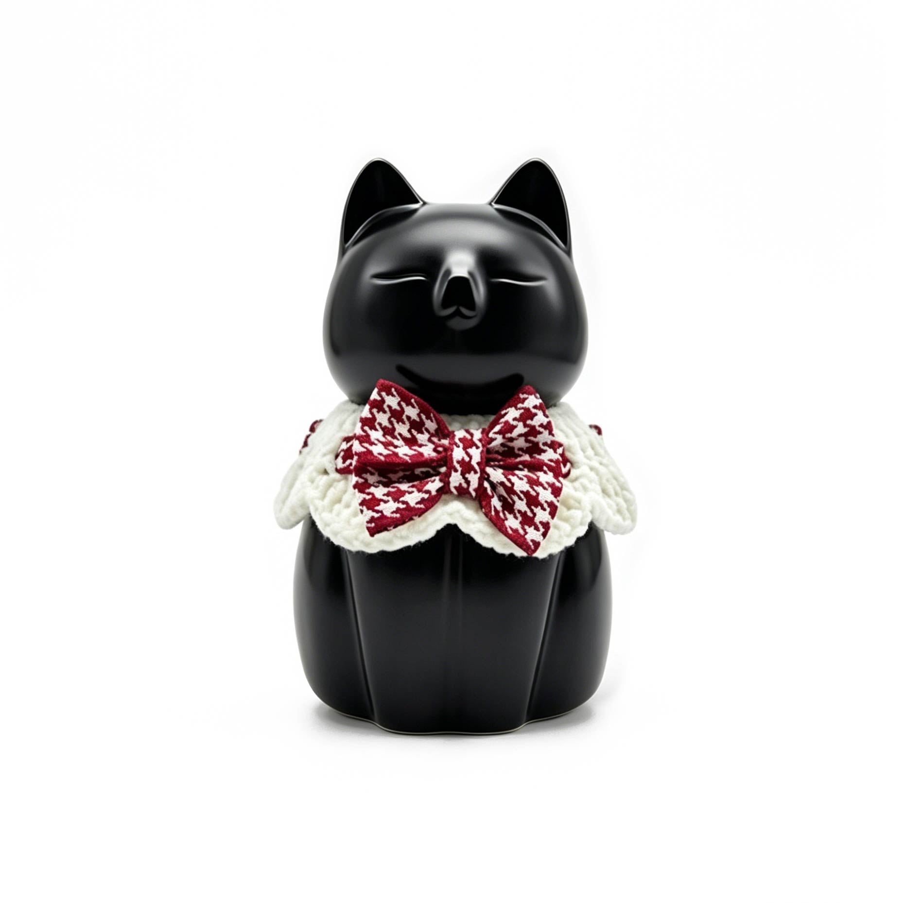 Black cat figurine with a red and white checkered bow tie on a white background