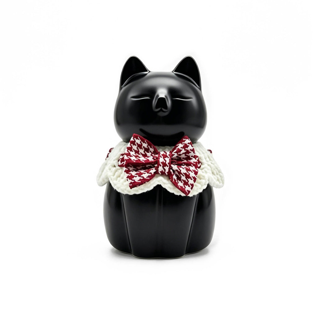 Black cat figurine with a red and white checkered bow tie on a white background