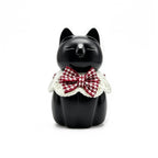 Black cat figurine with a red and white checkered bow tie on a white background