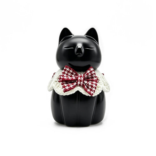 Black cat figurine with a red and white checkered bow tie on a white background