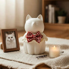 Cat-shaped night light with a bow tie on a table with a photo frame and candle.