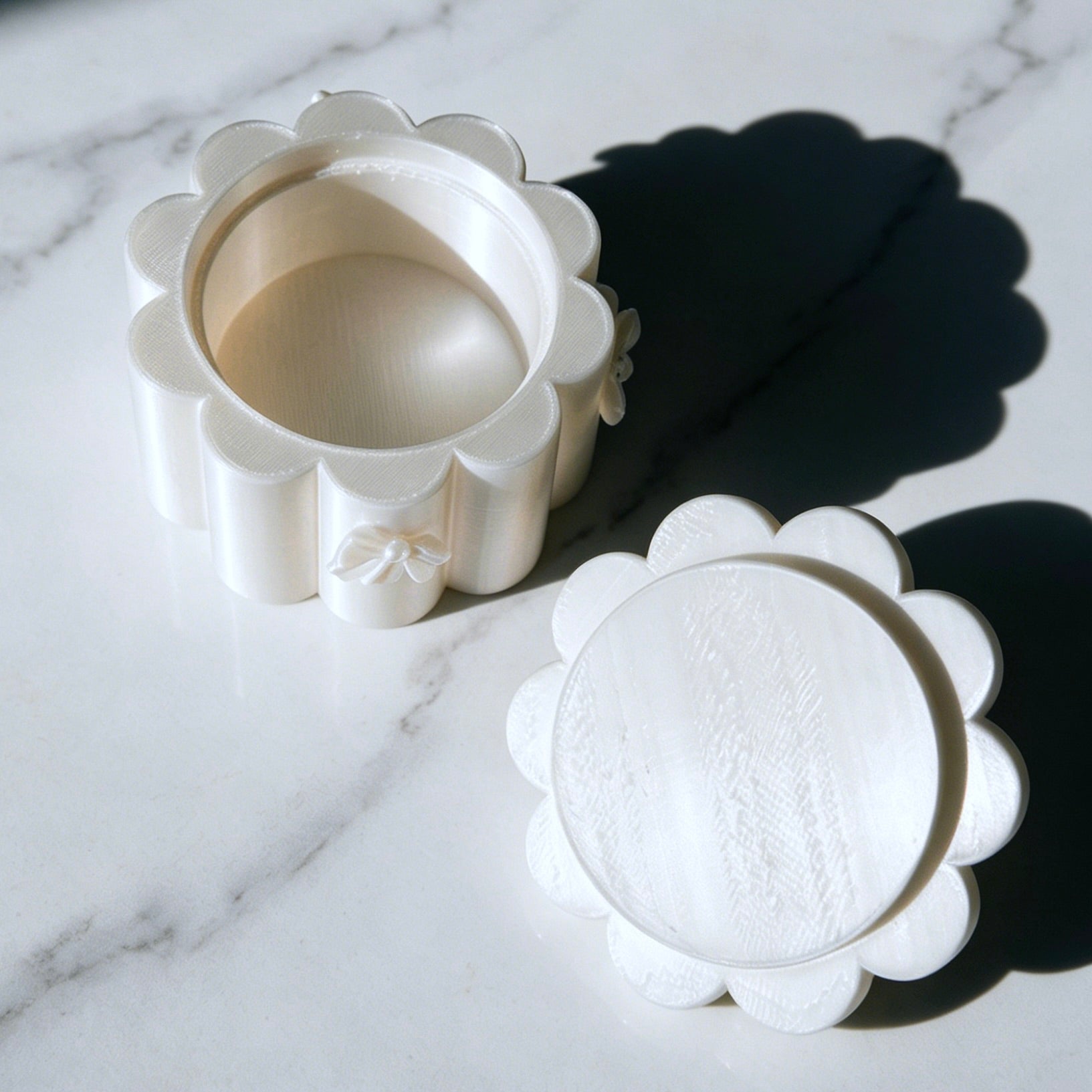White ceramic flower-shaped container on a marble surface