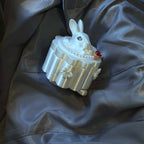 Decorative rabbit-shaped jewelry box with pearls and gemstones on a dark fabric background