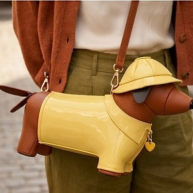 Dog-shaped handbag with a yellow raincoat and hat held by a person.