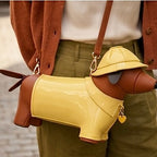 Dog-shaped handbag with a yellow raincoat and hat held by a person.