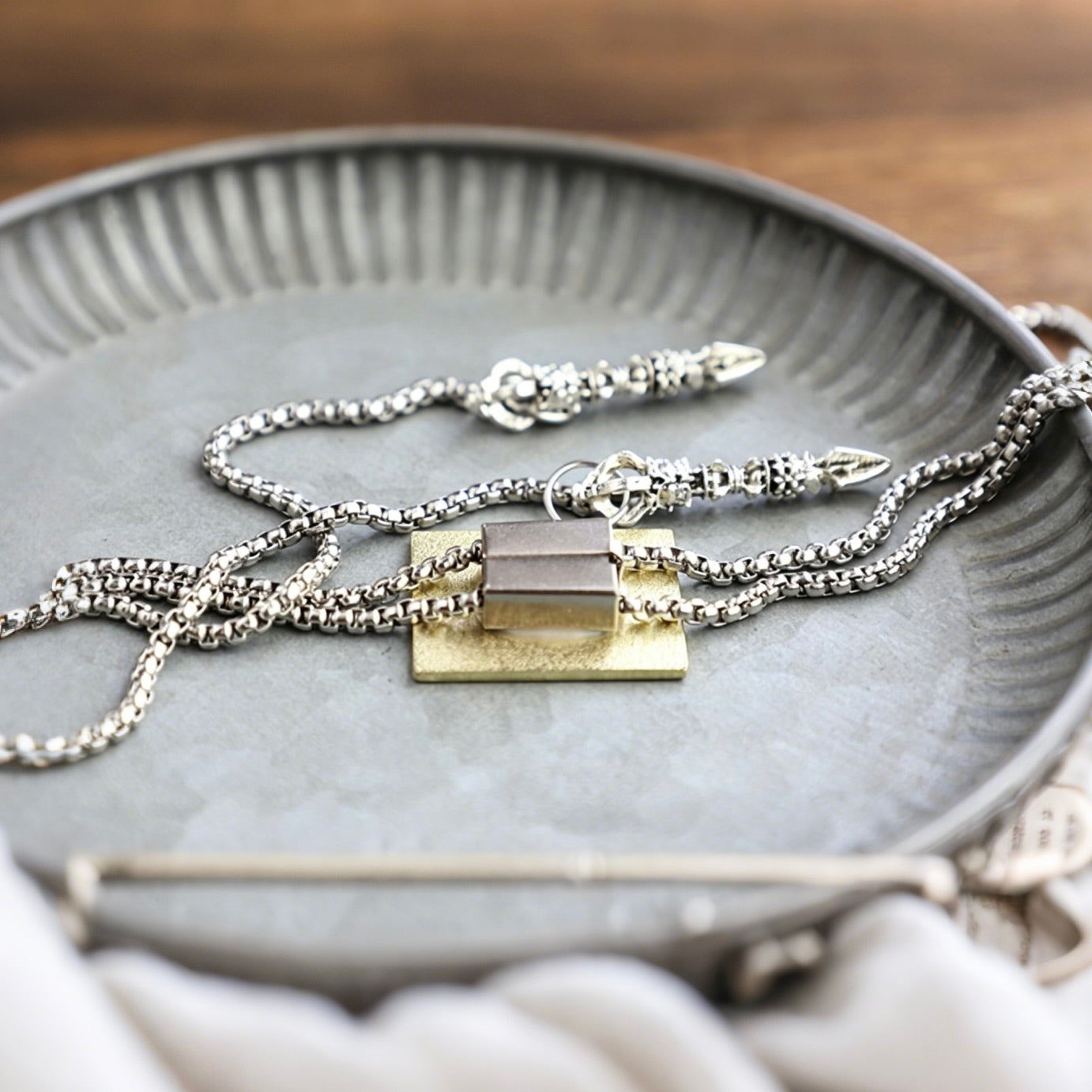 Silver necklaces with gold pendants on a gray textured plate