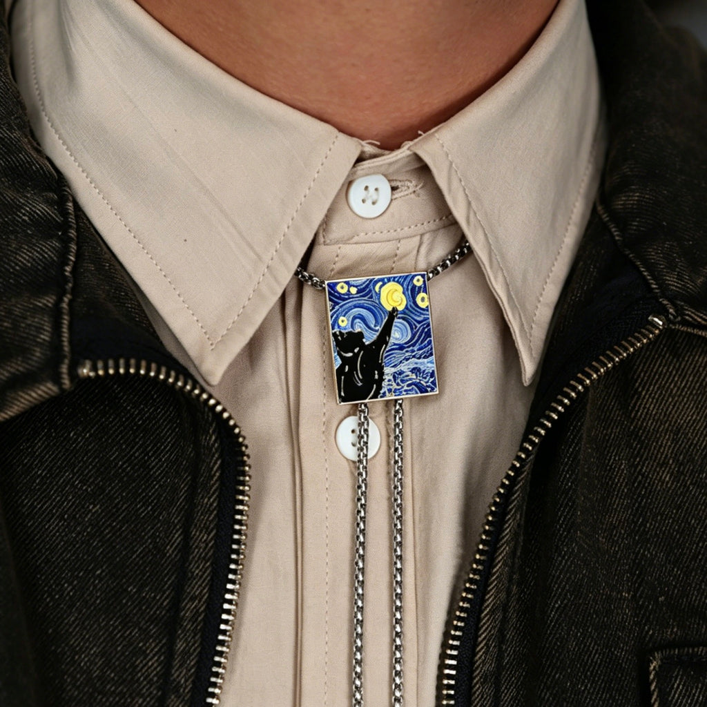 Person wearing a brooch with a black cat design on a beige shirt and dark jacket.