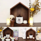 Decorative shelf with candles, flowers, and a cat-themed jar against a white background.