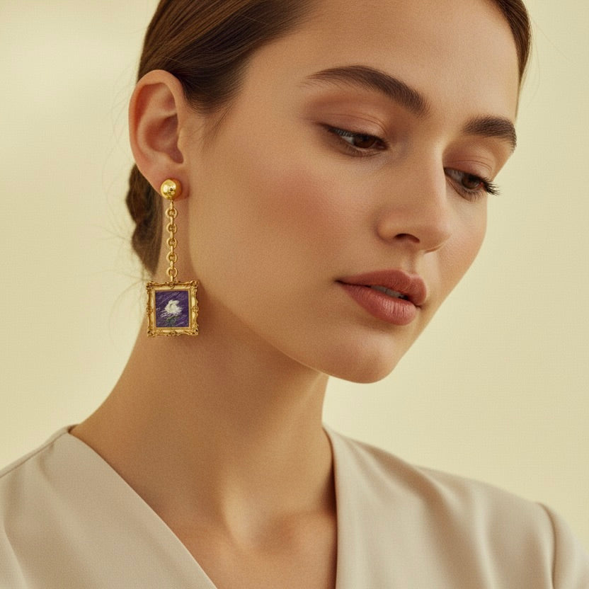 Close-up of a woman wearing a gold earring with a blue gemstone on a beige background
