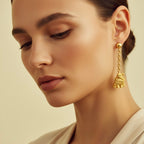 Close-up of a woman wearing gold earrings against a beige background