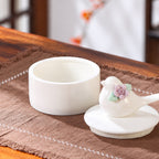 Open ivory ceramic bird memorial urn with the bird-shaped floral lid placed beside the empty interior