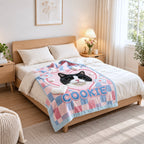 Pink and blue Cookie cat portrait blanket spread across a bed in a bright bedroom