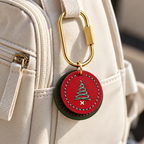 Layered red and green cowhide Christmas tree pet tag attached to a beige backpack