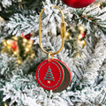 Layered red and green cowhide pet charm with a stitched Christmas tree design hanging on a holiday tree 