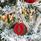 Layered red and green cowhide pet charm with a stitched Christmas tree design hanging on a holiday tree 