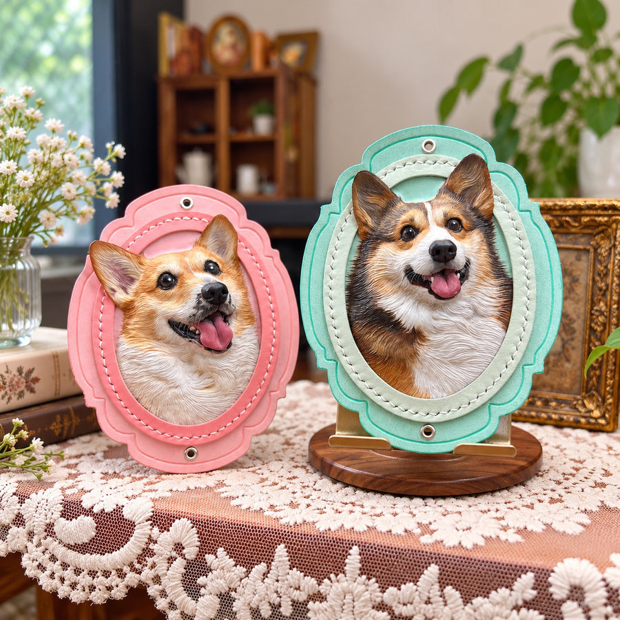 Two custom hand-carved leather Corgi portrait frames in pink and mint green, featuring detailed 3D dog portraits displayed on a lace-covered table.