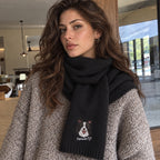 Woman wearing a black knit scarf embroidered with a black-and-white dog portrait, the name Sanwan and a heart