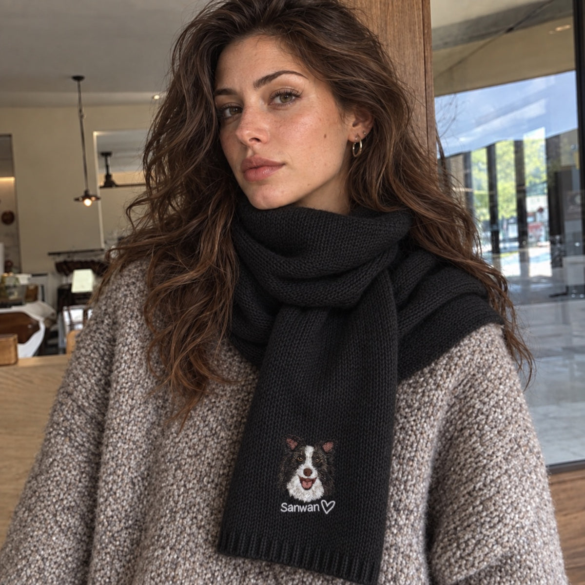 Woman wearing a black knit scarf embroidered with a black-and-white dog portrait, the name Sanwan and a heart