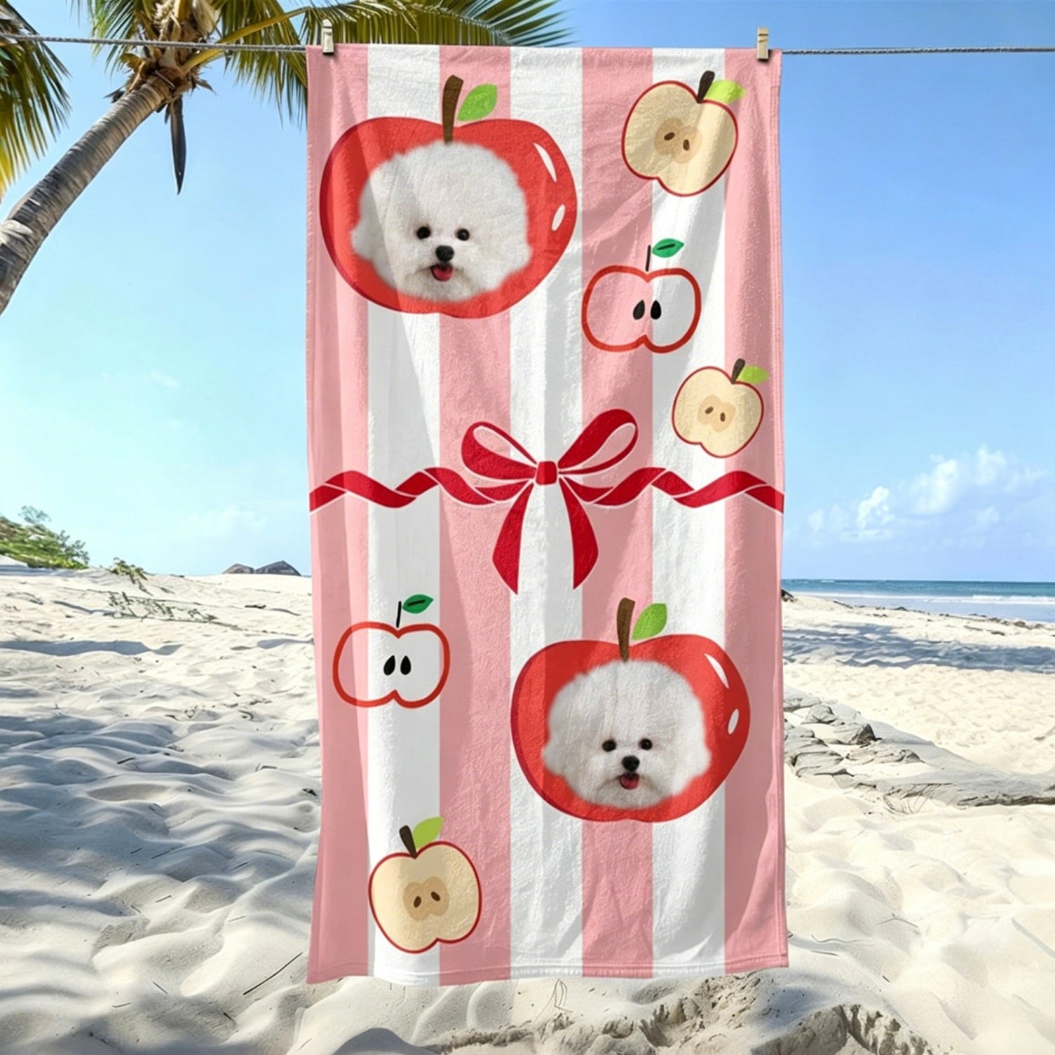 A pink striped custom dog portrait beach towel featuring a cute white puppy framed inside a red apple pattern, hanging on a sunny beach.