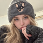 Woman wearing a gray knit beanie with a black-and-tan dog portrait and the embroidered number 66