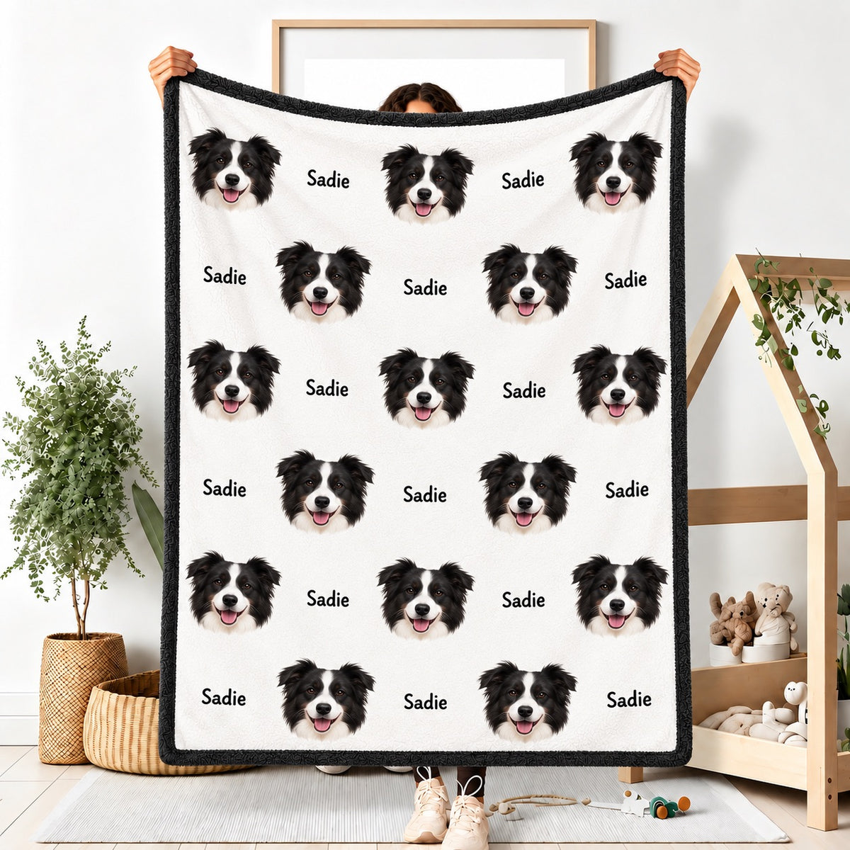 Person holding a white fleece blanket with a repeating black and white dog portrait pattern and the name Sadie