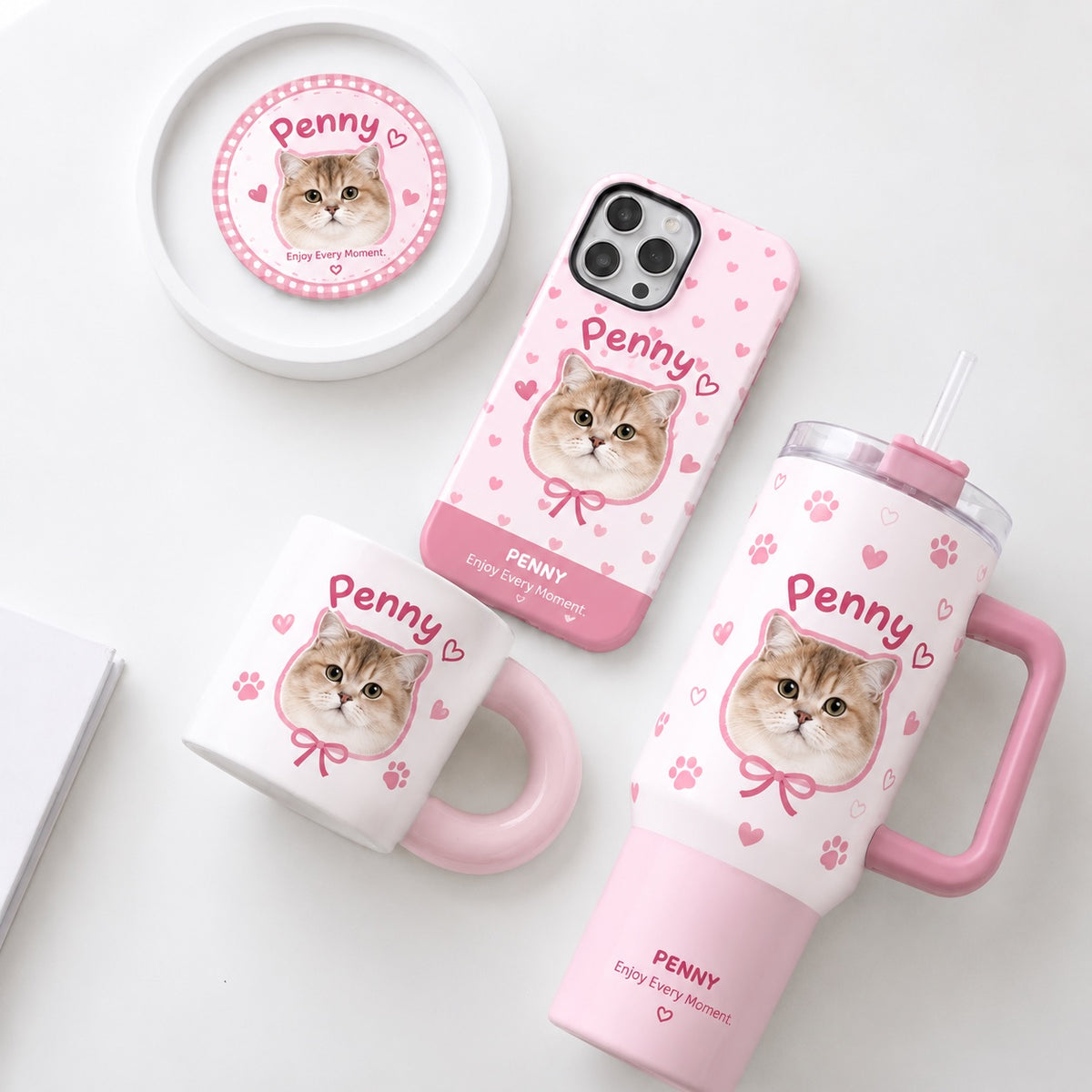 Custom pet portrait gift set in pink checkered pattern featuring personalized cat photo mug, tumbler, phone case, and pin badge next to a white cat.