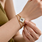 A model wearing a custom pet portrait mother-of-pearl clover bracelet in 18K gold.