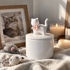 Ivory floral ceramic cat memorial urn displayed beside a framed cat photo, pet toys and memorial candles