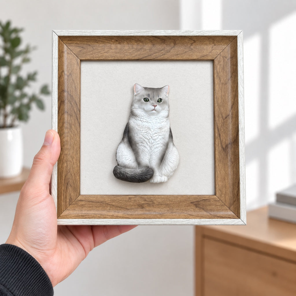 Hand holding a brown frame with light outer trim and a full-body silver-gray cat portrait with its tail curled forward