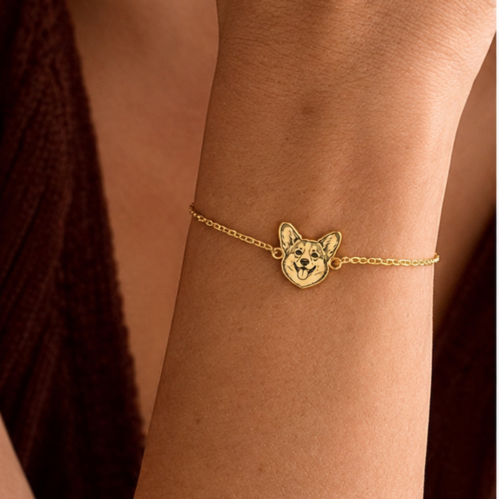 Gold-tone personalized Corgi portrait bracelet worn on the wrist in warm light