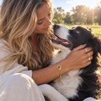 Woman holding a black and white dog while wearing a gold custom pet portrait bracelet