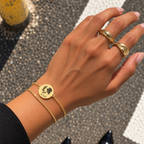 Gold double-chain keepsake bracelet with an engraved dog portrait worn on a wrist