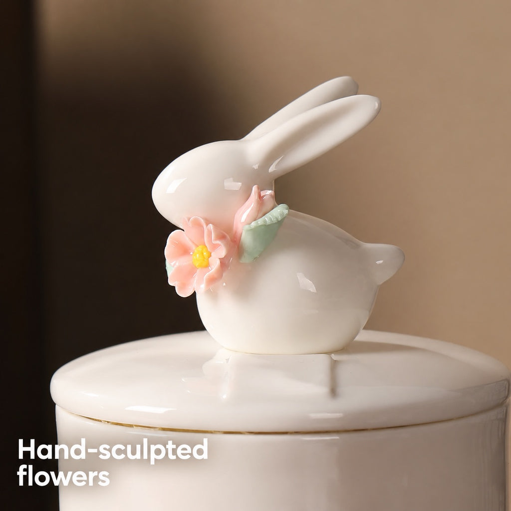 Close-up of the ivory rabbit figure with hand-sculpted pink flowers and green leaves on the ceramic urn lid