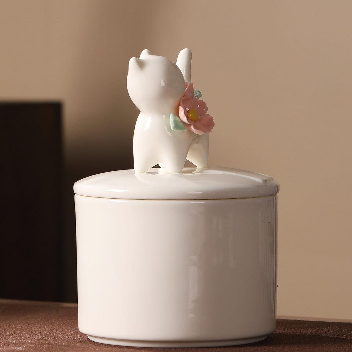 Rear view of a large ivory ceramic cat memorial urn with a standing cat figure and floral decoration on the lid