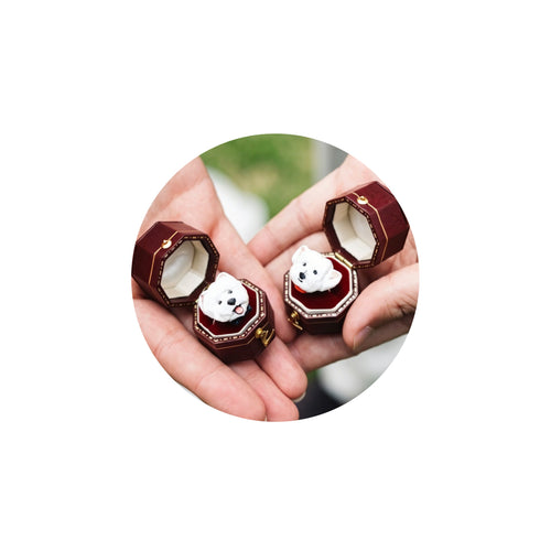 A hand holding two elegant dark red hexagonal velvet boxes containing bespoke 3D dog portrait rings, custom hand-sculpted as luxury wedding keepsakes.