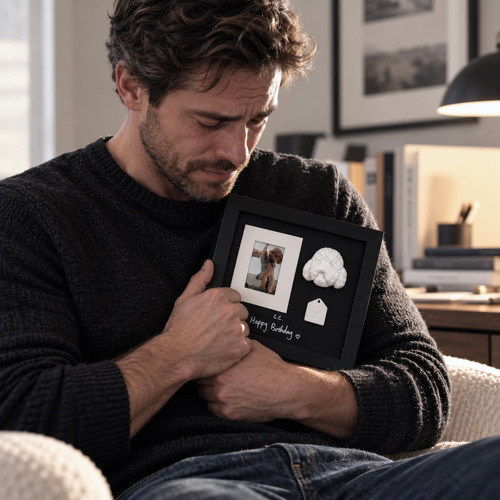 A grieving man holding a custom pet memorial shadow box featuring a 3D teddy dog portrait and photo