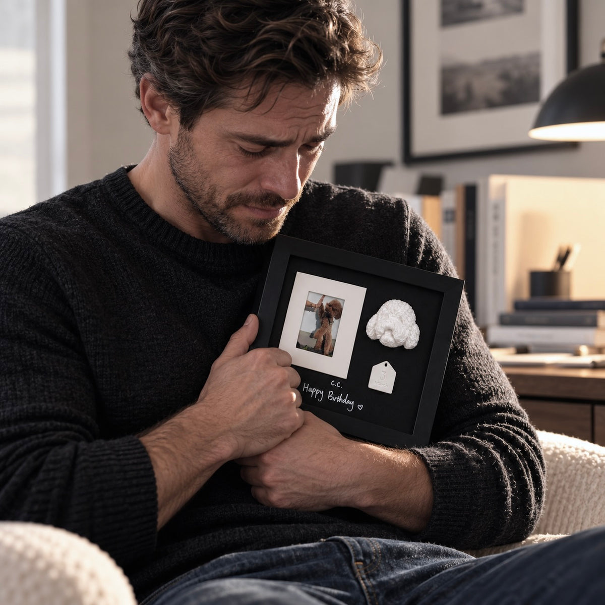A grieving man holding a custom pet memorial shadow box featuring a 3D teddy dog portrait and photo
