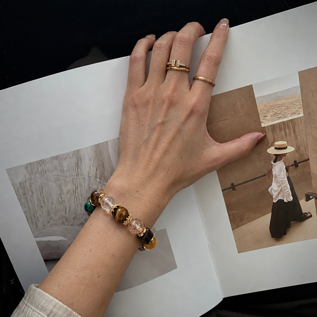 Hand wearing a crystal bead bracelet and gold rings next to a lookbook page showcasing pet and owner jewelry