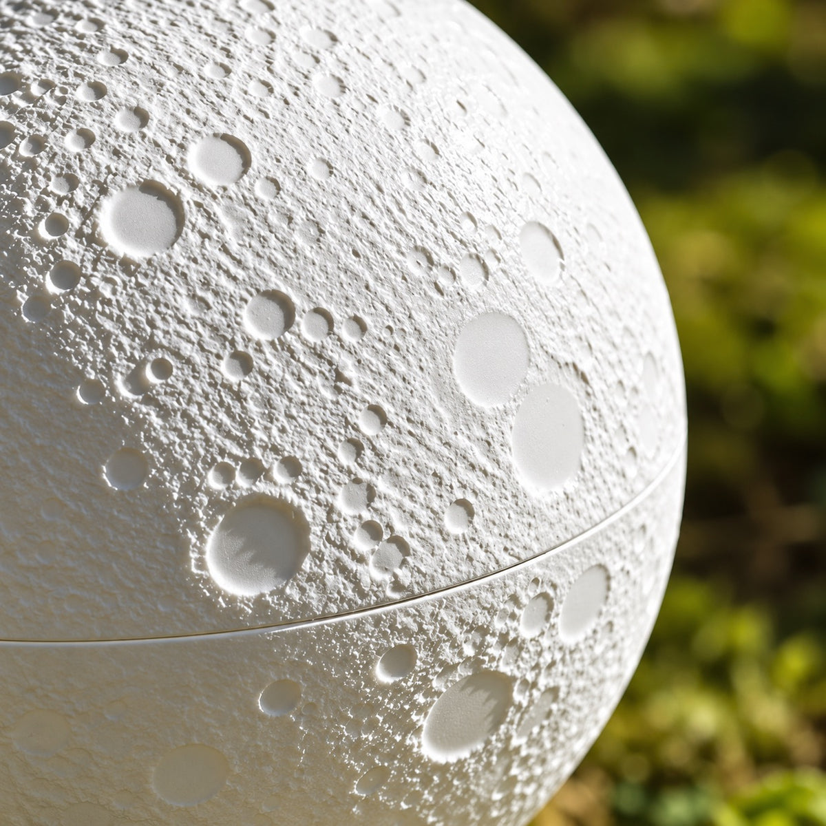 Close-up of the cratered moon texture and center seam on the white pet memorial urn