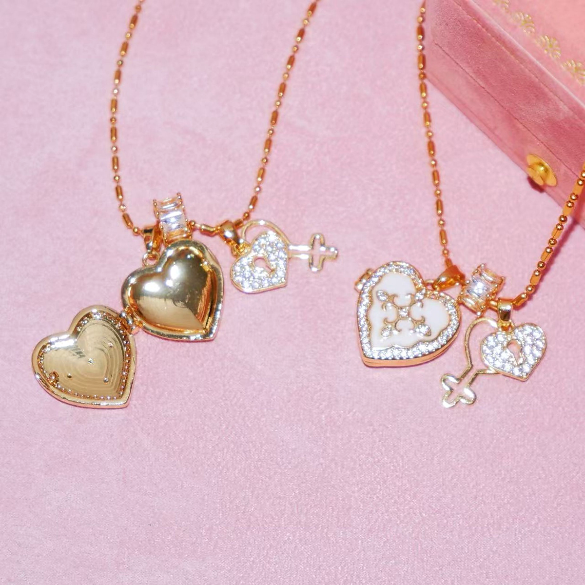 Open white heart photo locket beside a closed white locket and zircon key charm on pink fabric