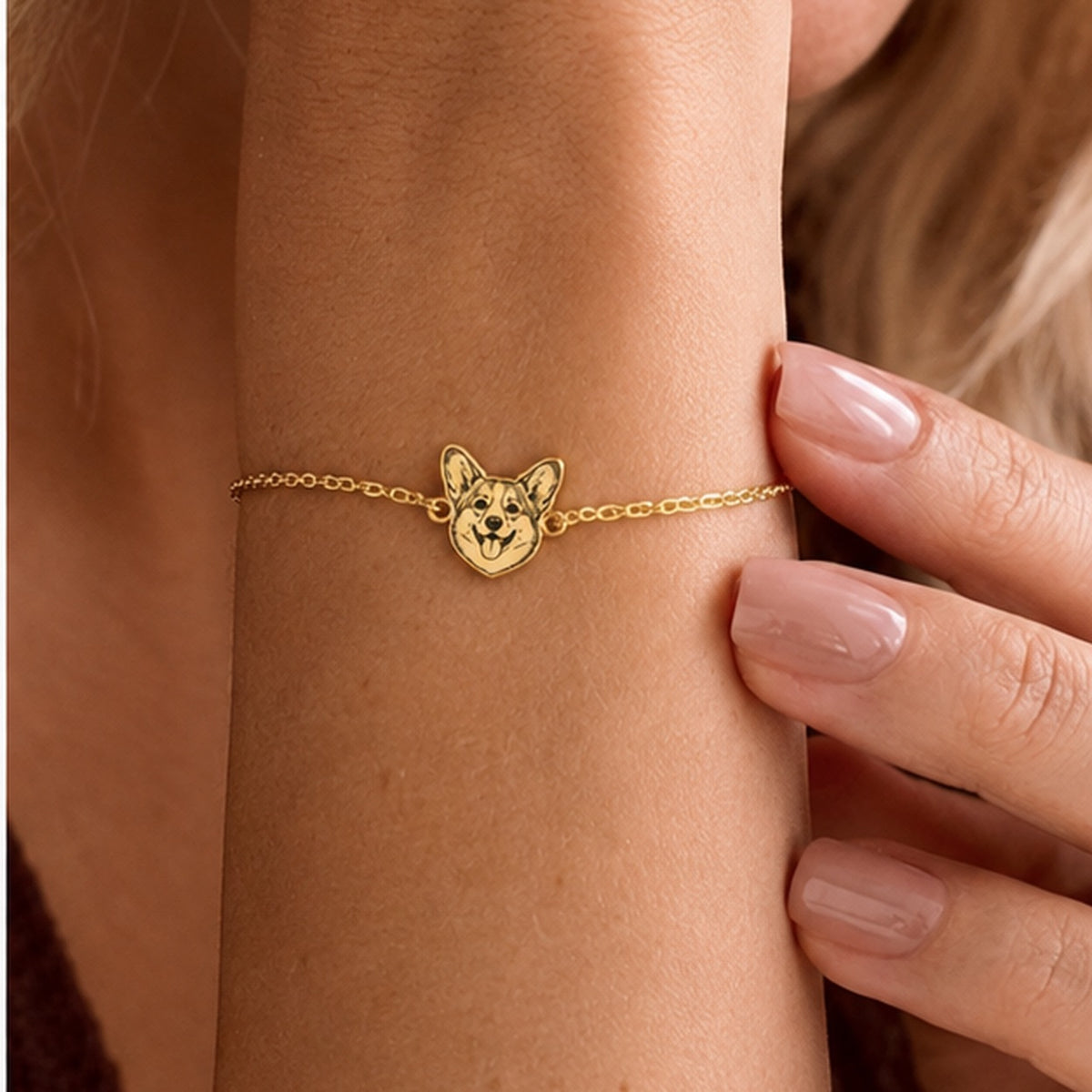 Close-up of a gold-tone custom Corgi face bracelet worn on the wrist