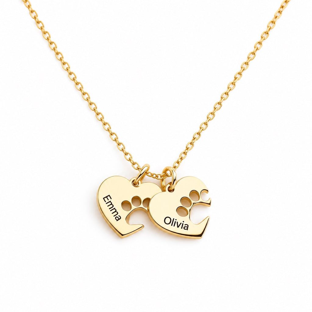 Close-up of a gold-tone necklace with two paw print heart charms engraved Emma and Olivia