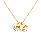 Close-up of a gold-tone necklace with two paw print heart charms engraved Emma and Olivia