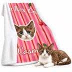 Pink striped cat portrait sherpa blanket with white fleece backing, displayed beside a brown-and-white cat