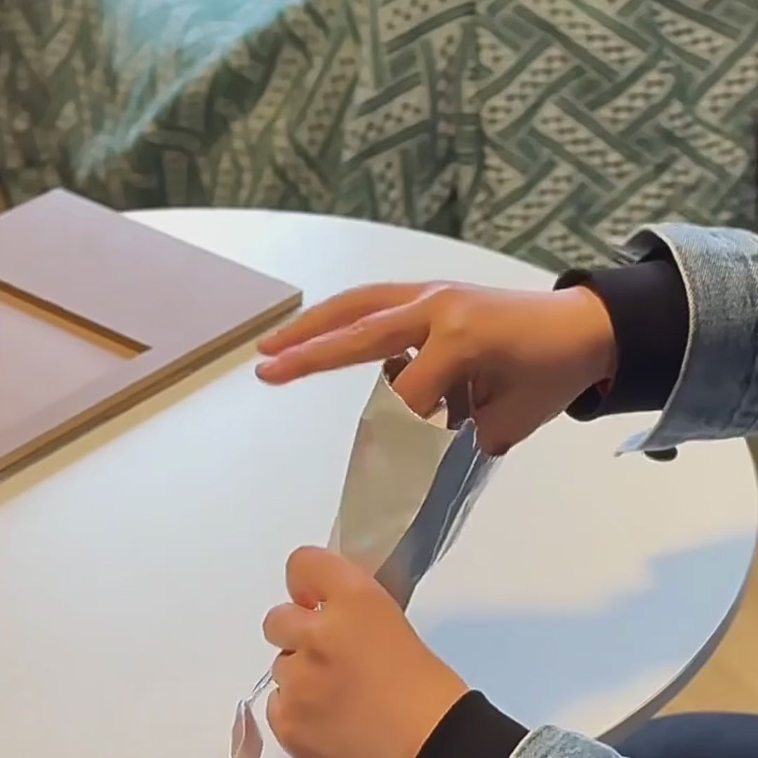 Hands demonstrating how to knead and roll out the soft clay for a pet paw print impression kit on a table.