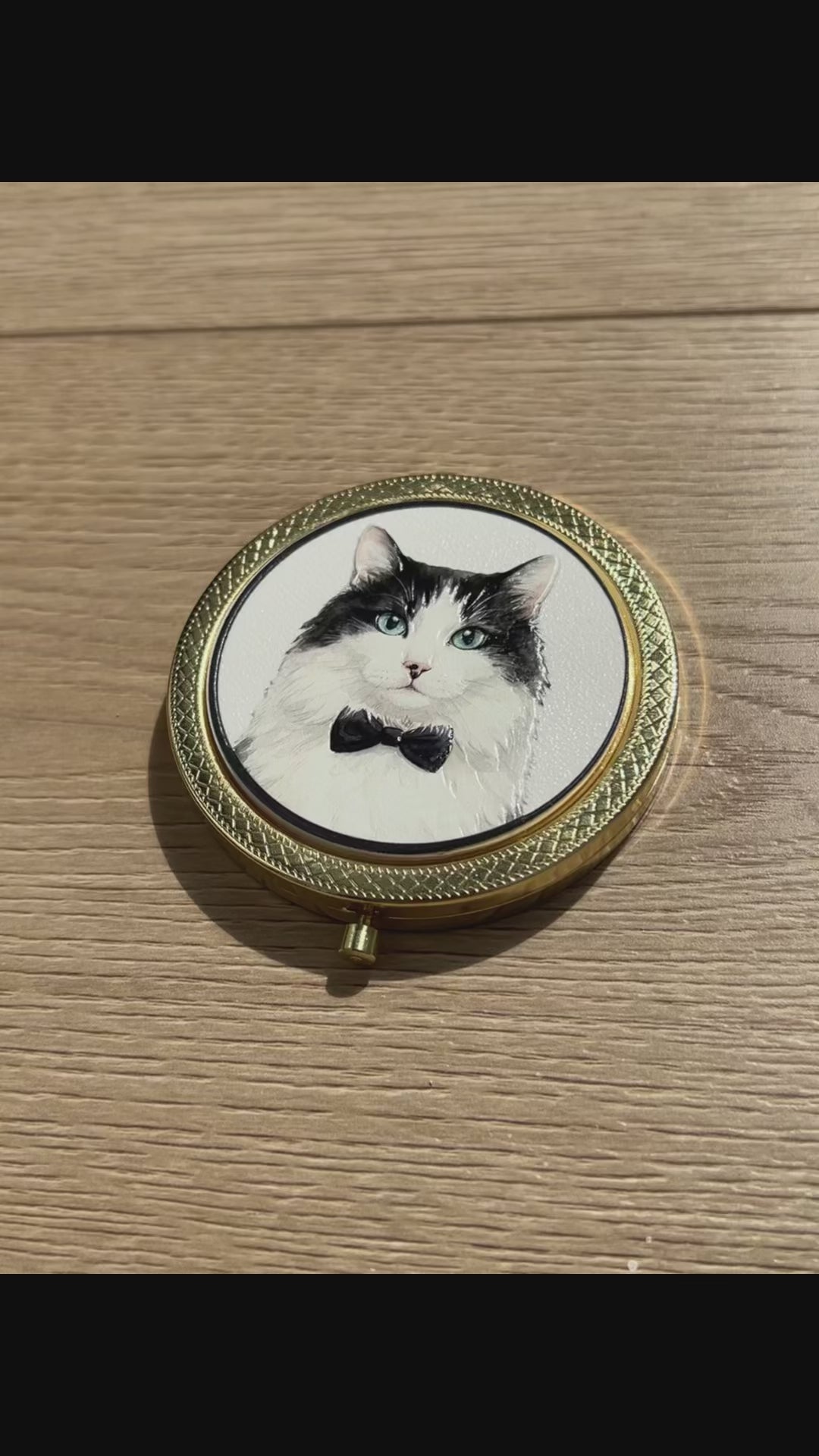 Video displaying a custom 3D embossed tuxedo cat compact mirror with a black bow tie, a luxury vintage makeup accessory by Memopaw.