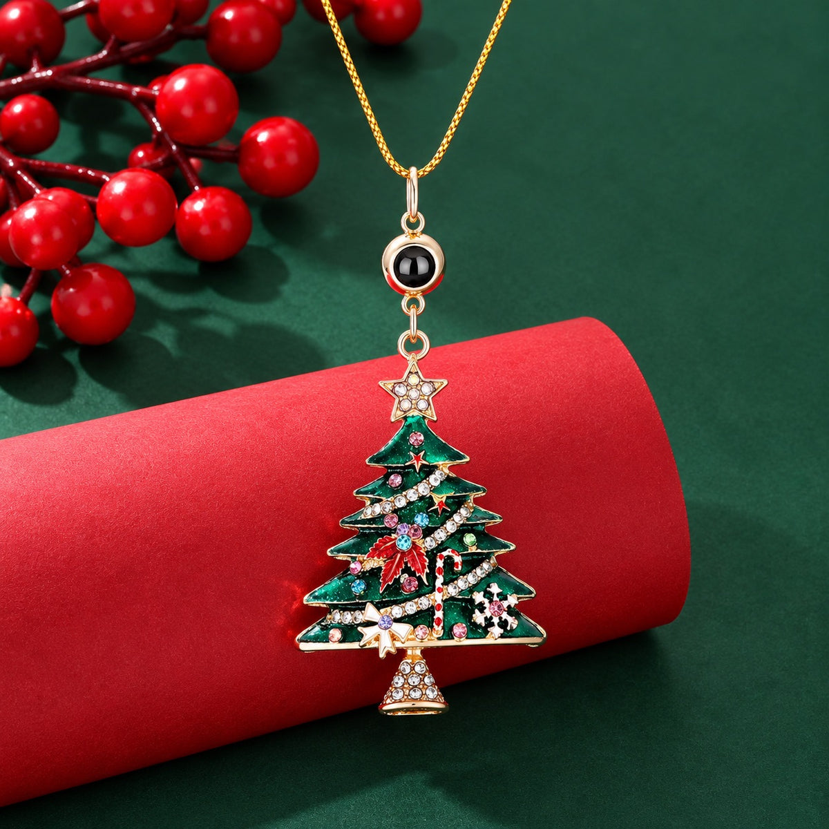 Close-up of a green jeweled Christmas tree projection pendant with gold-tone chain and round photo lens 