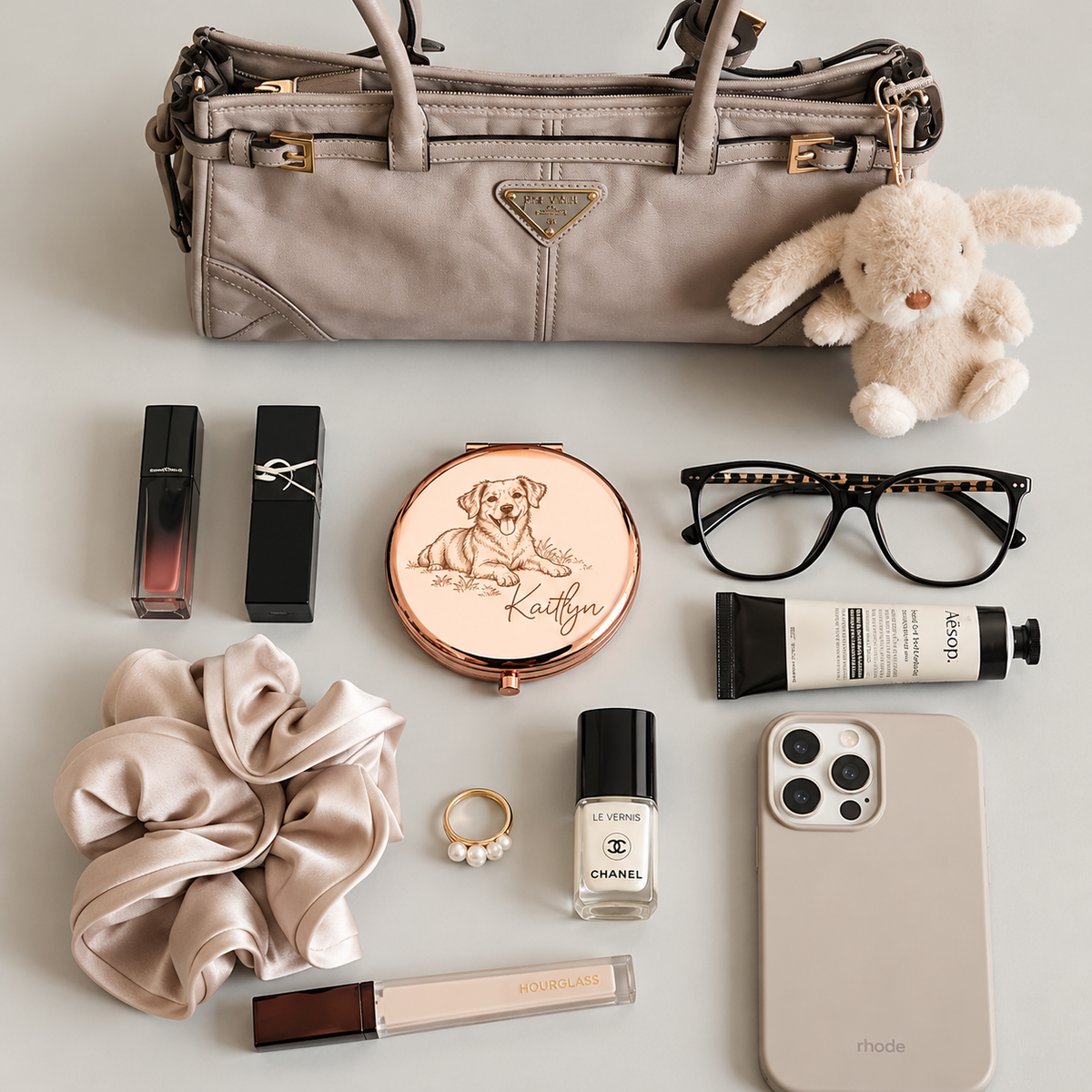 Rose gold-tone compact mirror engraved with a dog portrait and name among everyday bag accessories